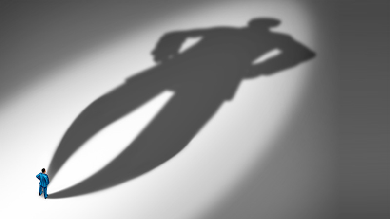 Project confidence as a businessman standing with a huge cast shadow as a metaphor for a confident personality and feeling of certainty in a 3D illustration style.