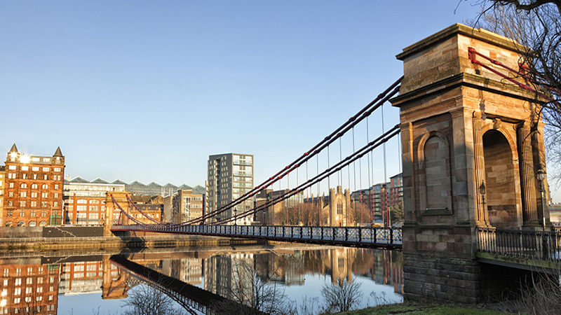 The view across the River Clyde in Glasgow to the city centre at the South Portland Street Bridge, a pedestrian suspension bridge built between 1851 and 1853.