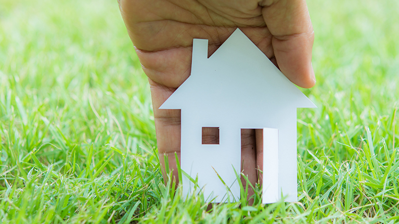 concept image of make house with white paper cut on green grass background